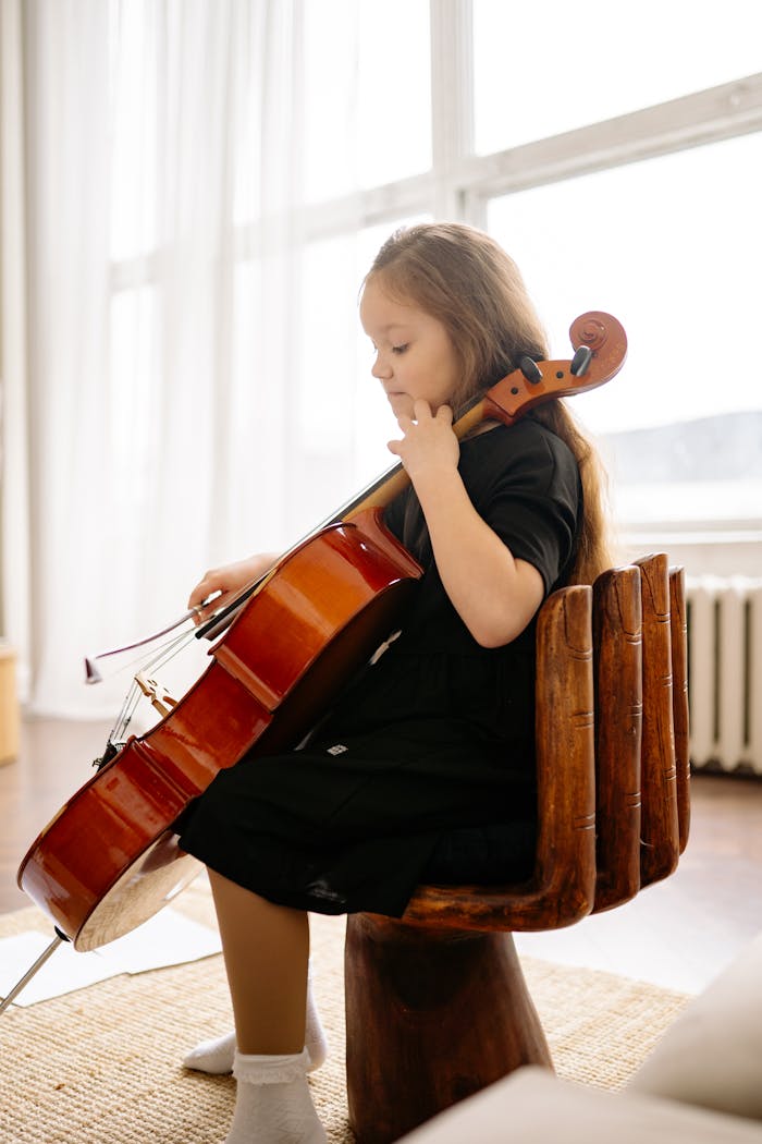 A young girl playing cello in a bright, cozy room, focusing on her music practice.